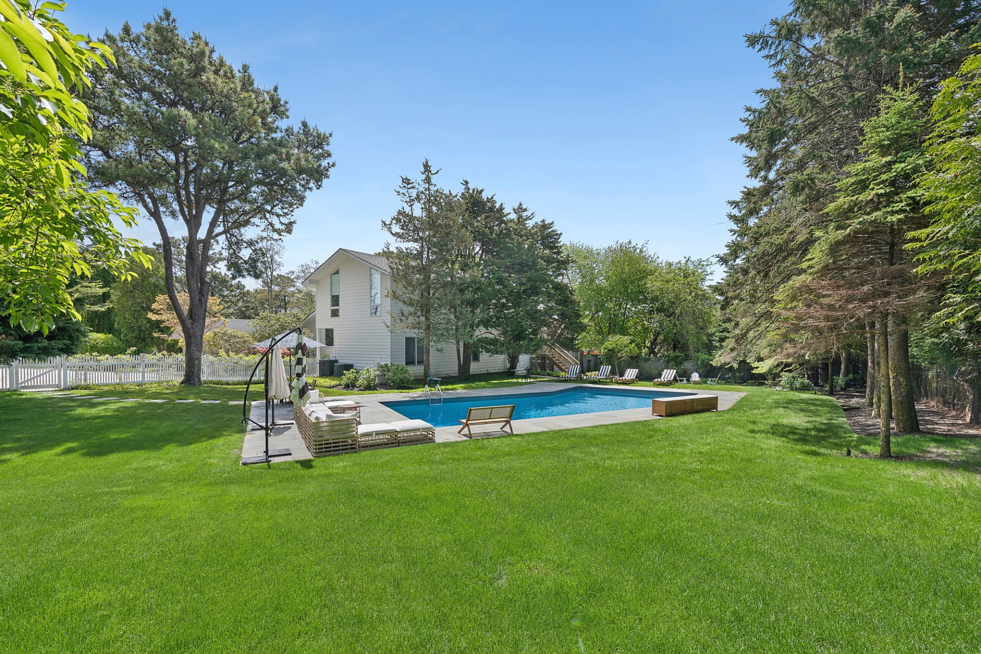 a view of a swimming pool with lawn chairs and a big yard