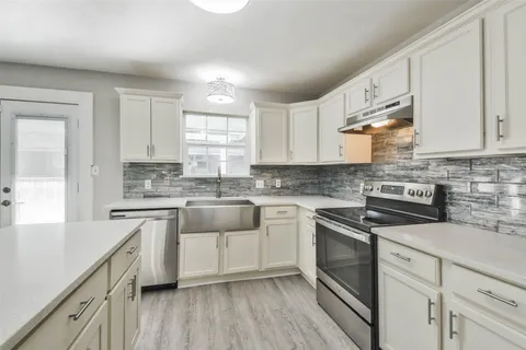 a kitchen with cabinets appliances a sink and a window