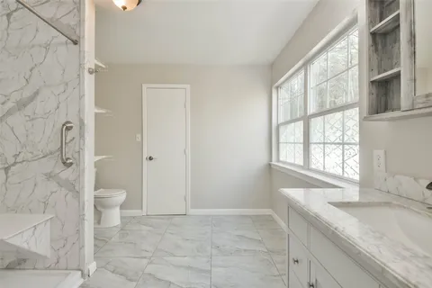 a bathroom with a granite countertop sink a toilet and a bathtub