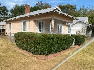 a view of a white house with a big yard plants and large tree