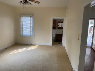 an empty room with windows and a chandelier fan