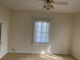 an empty room with windows and fan
