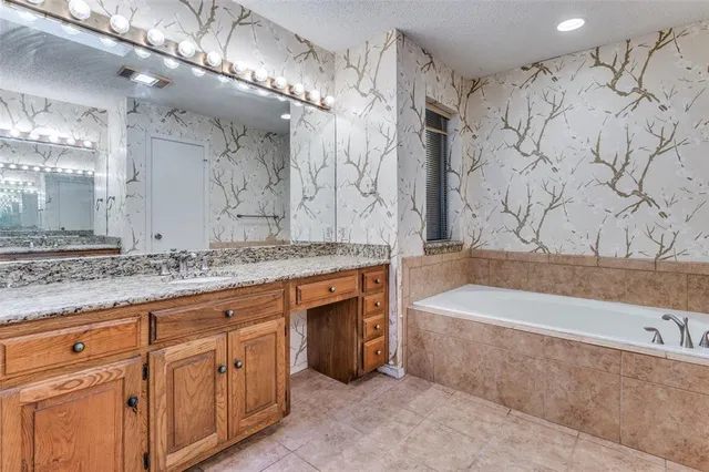 a spacious bathroom with a granite countertop sink a mirror a bathtub and shower
