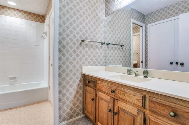 a bathroom with a granite countertop sink a mirror and a bathtub