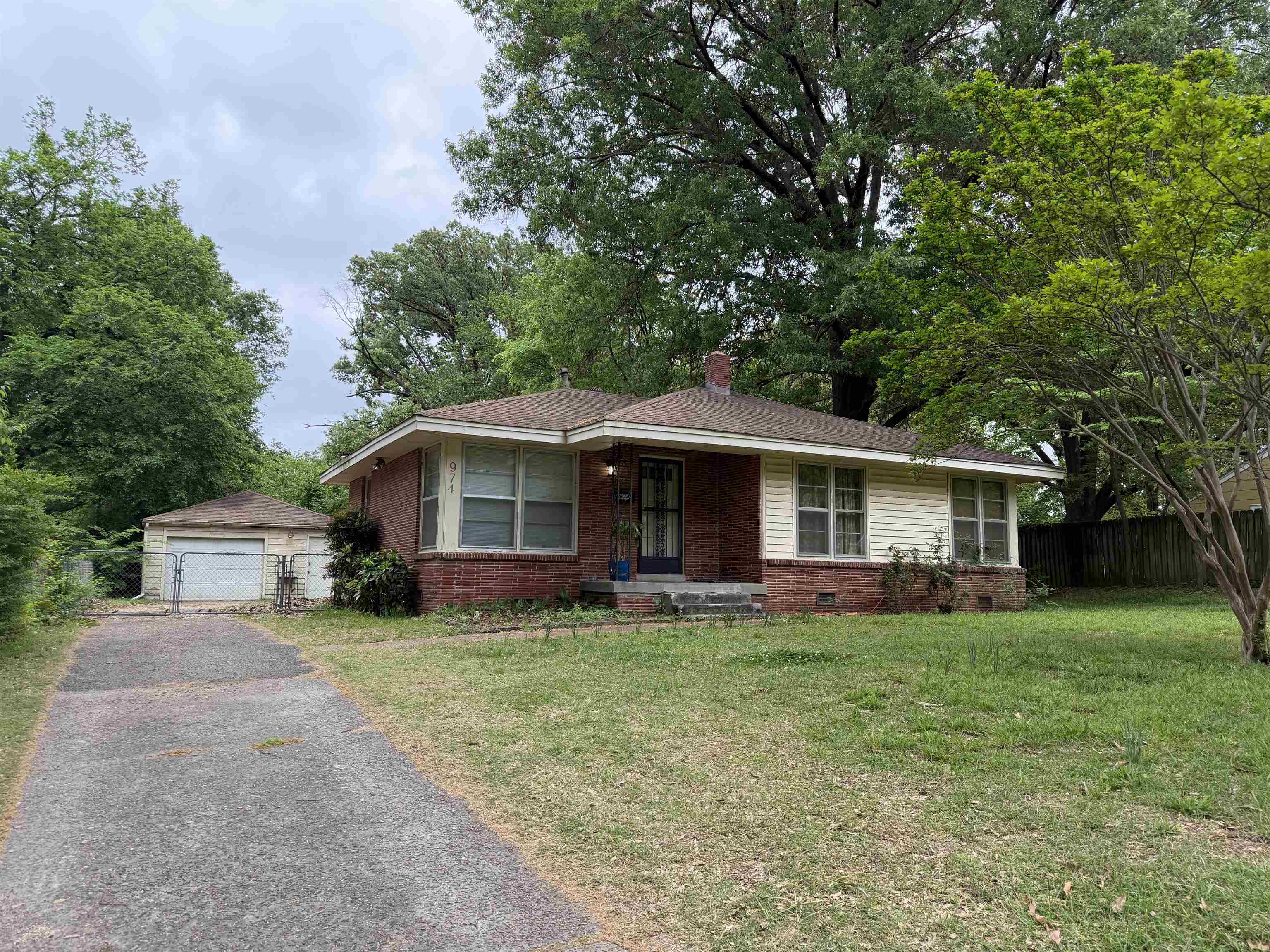 Ranch-style home with an outbuilding, brick siding, a detached garage, and a chimney