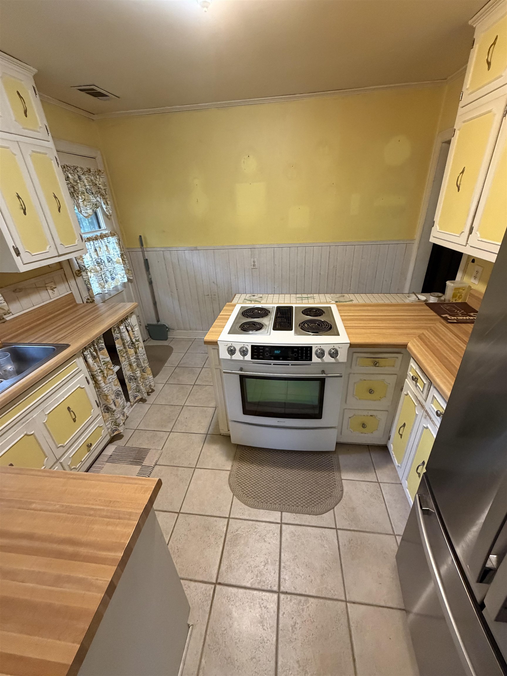 974 Tatum Road Memphis, TN 38122 - Photo 4 of 11 Kitchen with a wainscoted wall, wooden walls, white cabinetry, white electric stove, and freestanding refrigerator