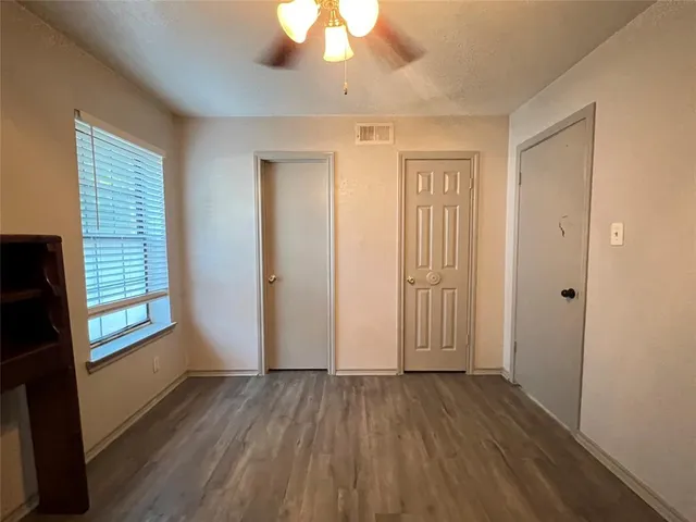 an empty room with wooden floor cabinet and windows
