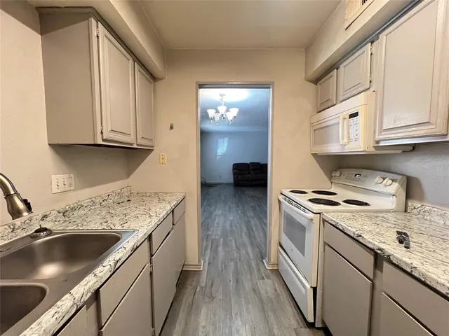a kitchen with granite countertop a sink a stove and cabinets