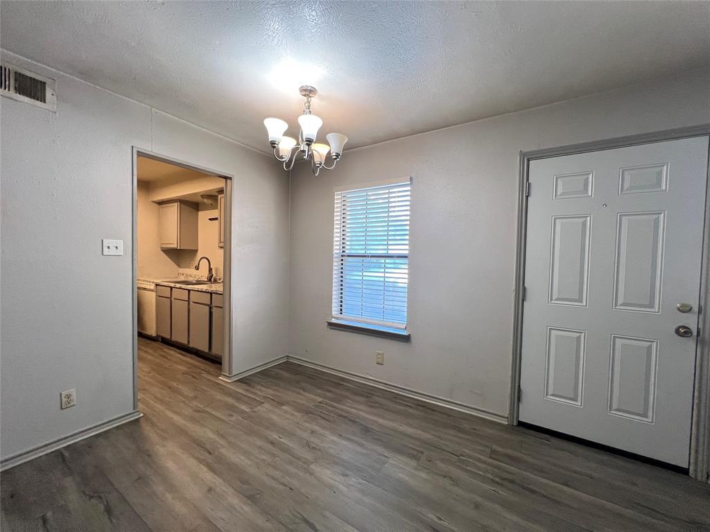 1108 North Elm Street, Unit 3 Denton, TX 76201 - Photo 10 of 15 an empty room with wooden floor chandelier and windows