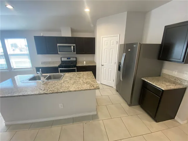 a kitchen with granite countertop a refrigerator and a sink
