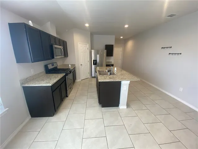 a kitchen with stainless steel appliances a sink a stove a microwave a counter top space and cabinets