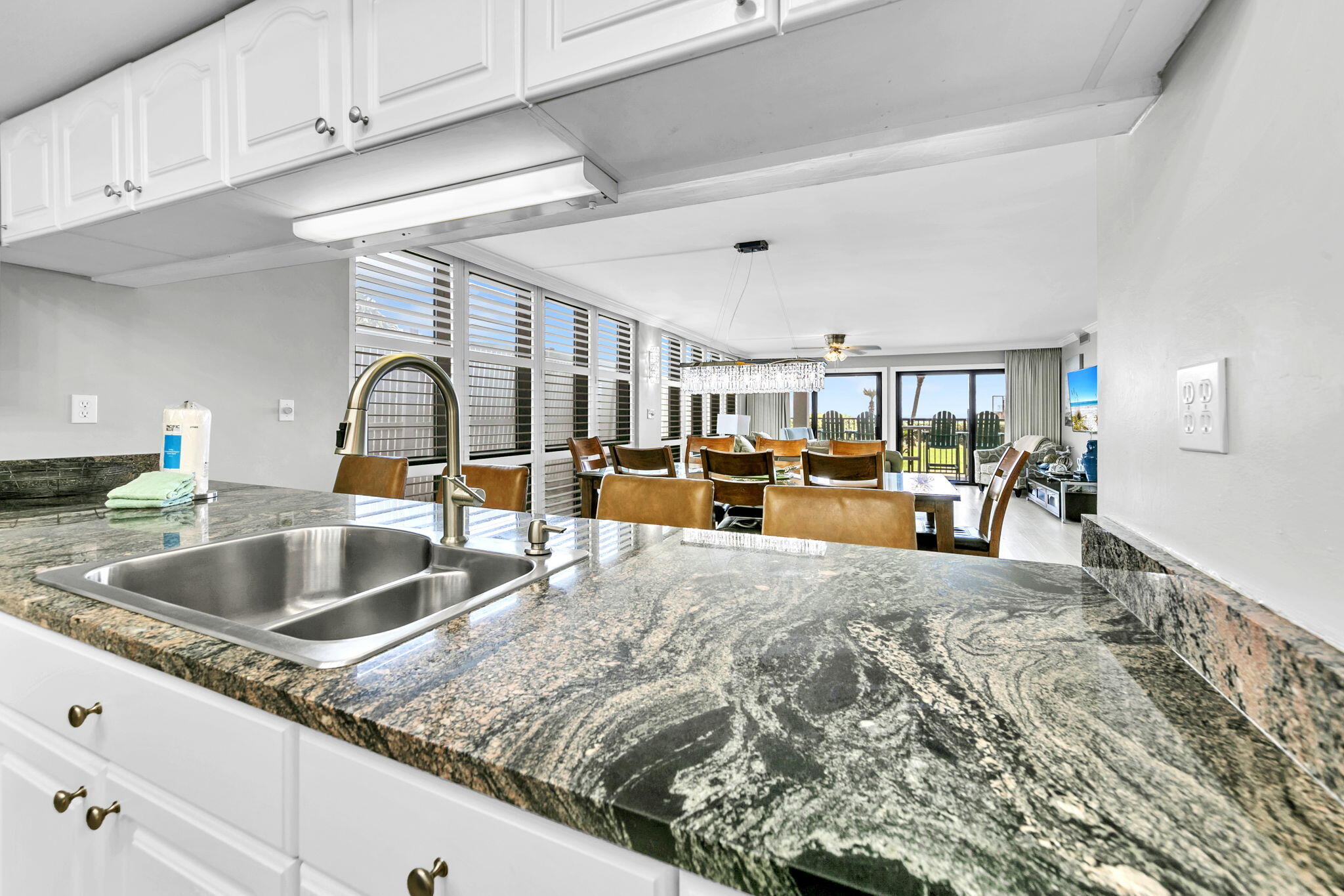 1044 Highway 98, Unit 101 Destin, FL 32541 - Photo 8 of 33 a kitchen with kitchen island granite countertop a sink and white cabinets with wooden floor