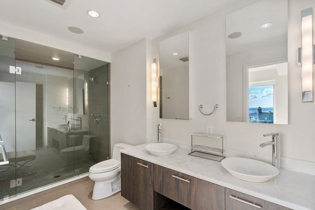 a bathroom with a toilet a sink a mirror a shower a vanity and window