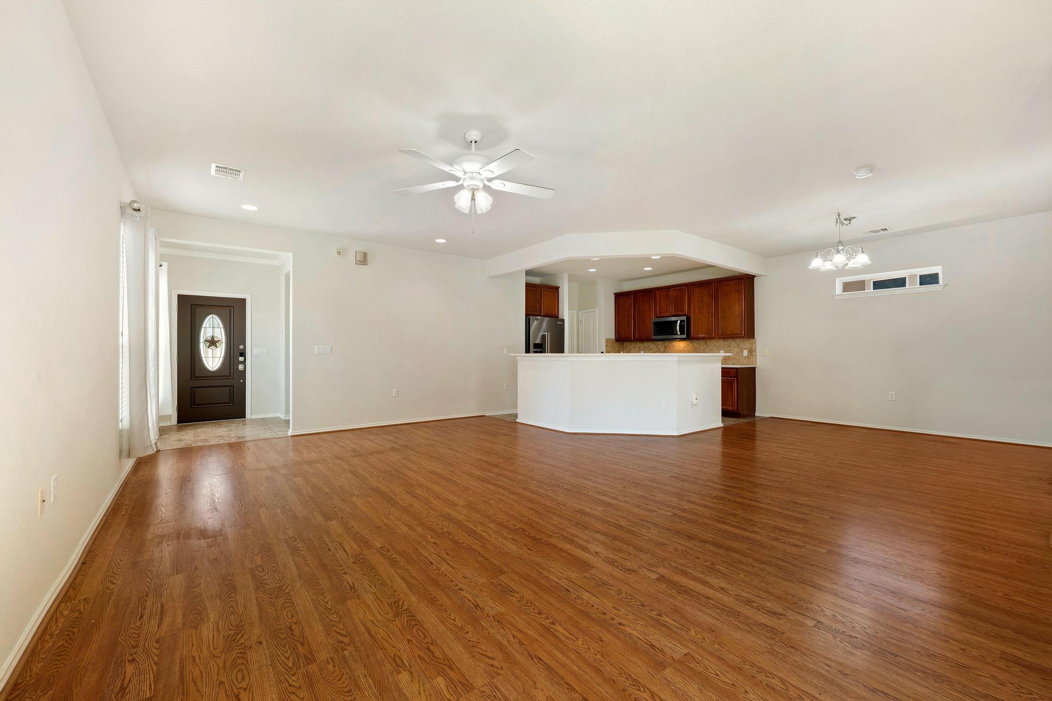520 Mill Pond Path Georgetown, TX 78633 - Photo 11 of 38 Rich hardwood like floors flow through this open-concept living space, connecting to a functional kitchen with a breakfast bar.