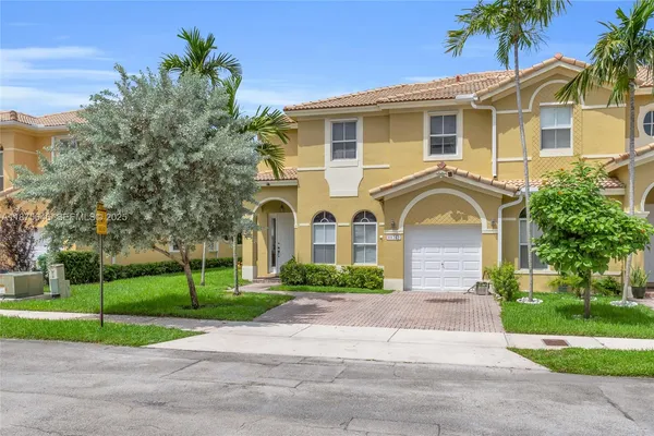 a front view of a house with a yard and potted plants