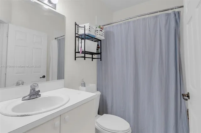 a bathroom with a sink a toilet a mirror and shower curtain