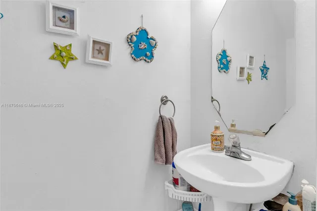 a bathroom with a sink a mirror and painting on the wall