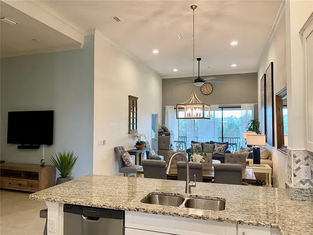 a kitchen with stainless steel appliances a refrigerator a sink dishwasher a stove and a dining table with wooden floor