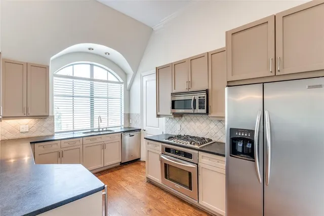 a kitchen with stainless steel appliances granite countertop a stove a sink and a refrigerator
