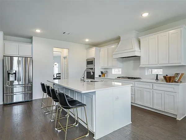 a kitchen with stainless steel appliances a table chairs refrigerator and cabinets