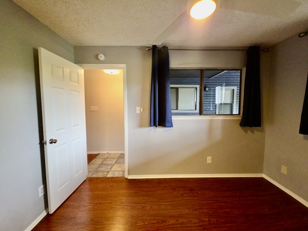 2500 Burleson Road, Unit 521 Austin, TX 78741 - Photo 15 of 20 Room featuring wood-finish flooring, light gray wall paint, and a window with dark curtains