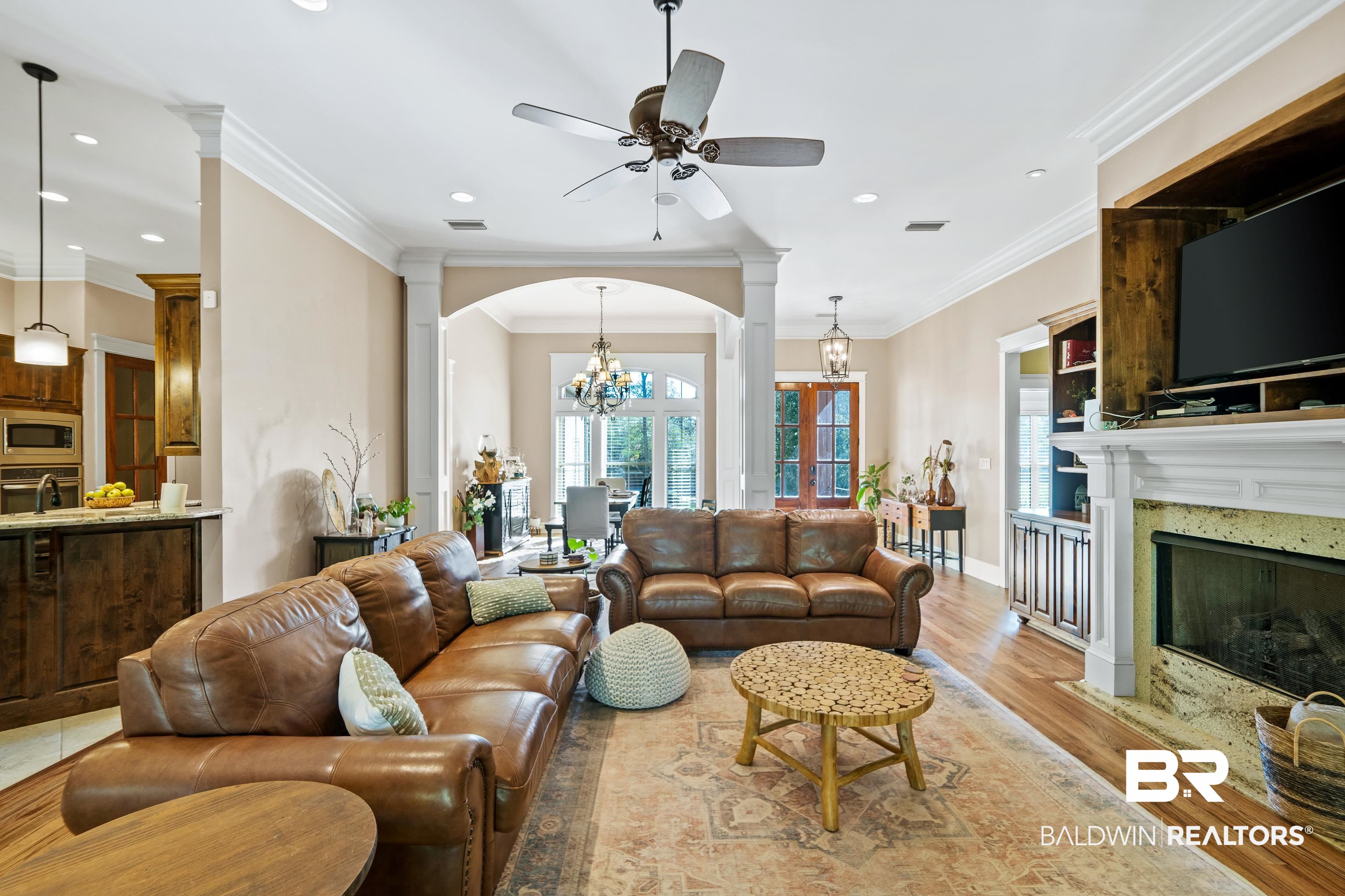 31829 Butler Drive Daphne, AL 36527 - Photo 12 of 48 Living room featuring ceiling fan with notable chandelier, light wood-type flooring, a fireplace, and crown molding