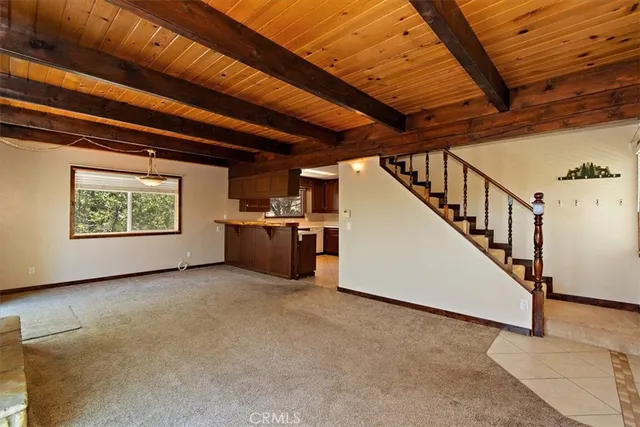 a view of an empty room with wooden floor and stairs