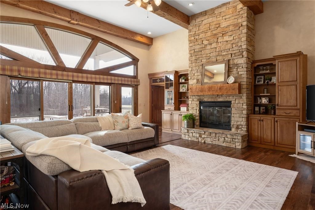 9419 Robinson Road Chardon, OH 44024 - Photo 4 of 49 Great room featuring a floor-to-ceiling stone fireplace with a wood mantle, exposed wood ceiling beams, and expansive windows