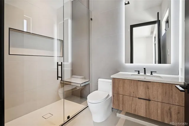 a bathroom with a granite countertop sink toilet a mirror and shower