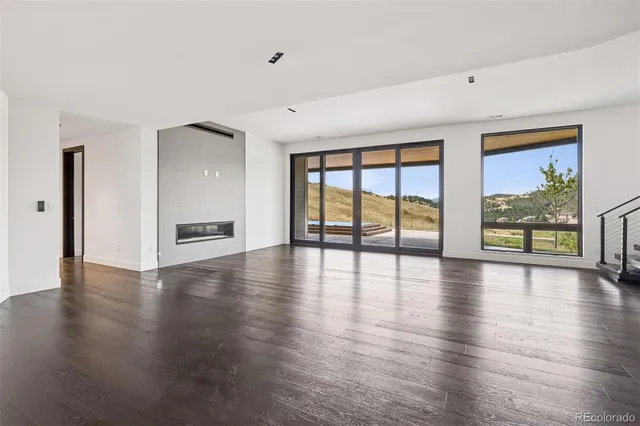 a view of an empty room with window and wooden floor