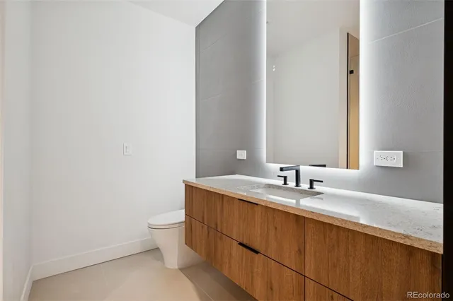 a bathroom with a granite countertop sink a toilet and a mirror