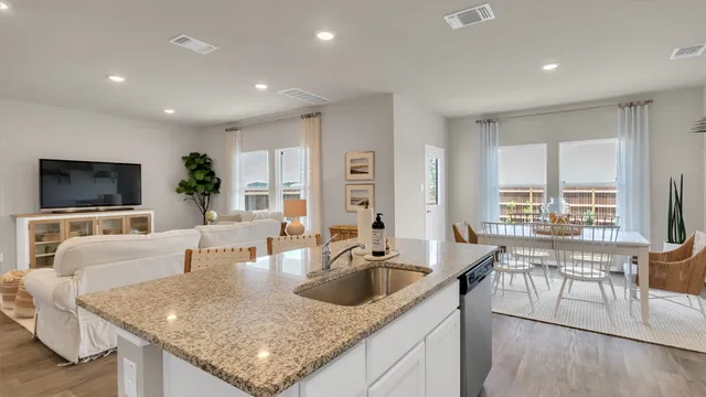 a kitchen with granite countertop a stove a sink a dining table and chairs