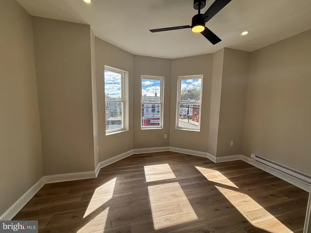 a view of an empty room with window and chandelier fan