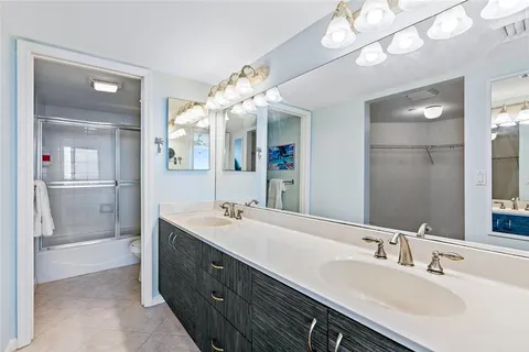 a spacious bathroom with a double vanity sink a mirror and a shower