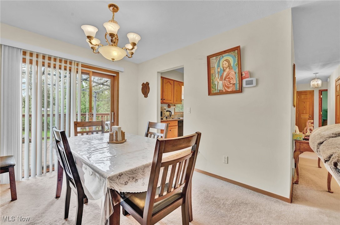 7676 Brecksville Road Independence, OH 44131 - Photo 8 of 32 Dining space with light colored carpet, baseboards, and a notable chandelier