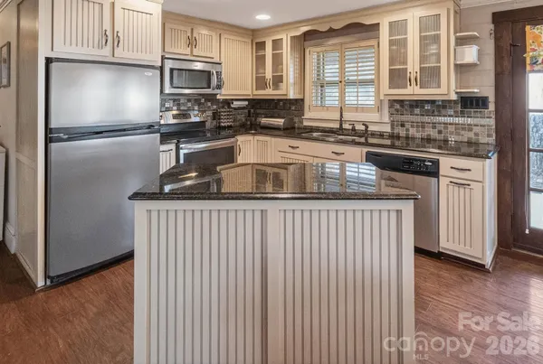 a kitchen with stainless steel appliances granite countertop a refrigerator a sink a stove and white cabinets