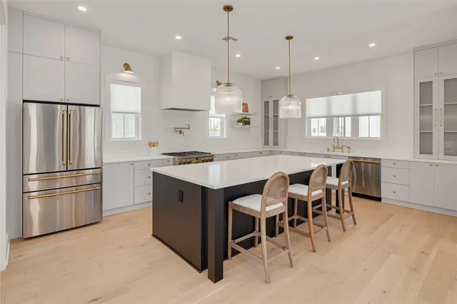 a kitchen with stainless steel appliances granite countertop a table chairs sink refrigerator and microwave