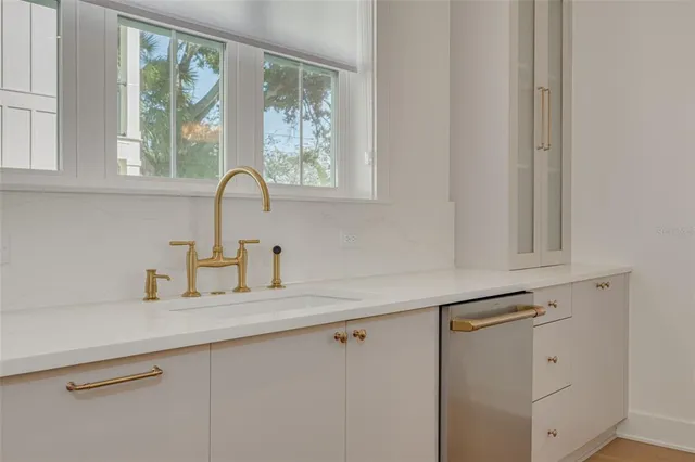 a kitchen with white cabinets and a window
