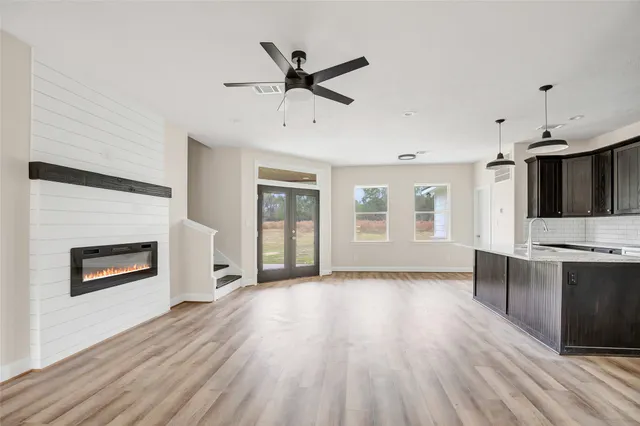 a view of a livingroom with a fireplace a ceiling fan and wooden floor