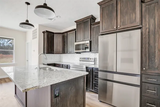 a kitchen with stainless steel appliances granite countertop a refrigerator a sink and a stove