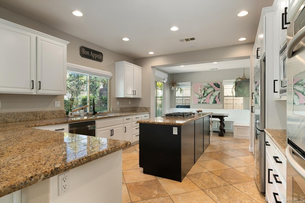 832 Genoa Way San Marcos, CA 92078 - Photo 18 of 42 a kitchen with kitchen island granite countertop a sink counter top space appliances and cabinets