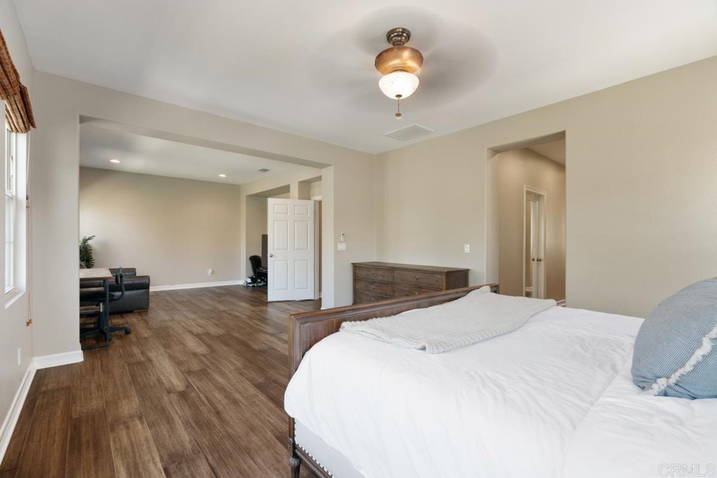 832 Genoa Way San Marcos, CA 92078 - Photo 30 of 42 a spacious bedroom with a bed and a chandelier