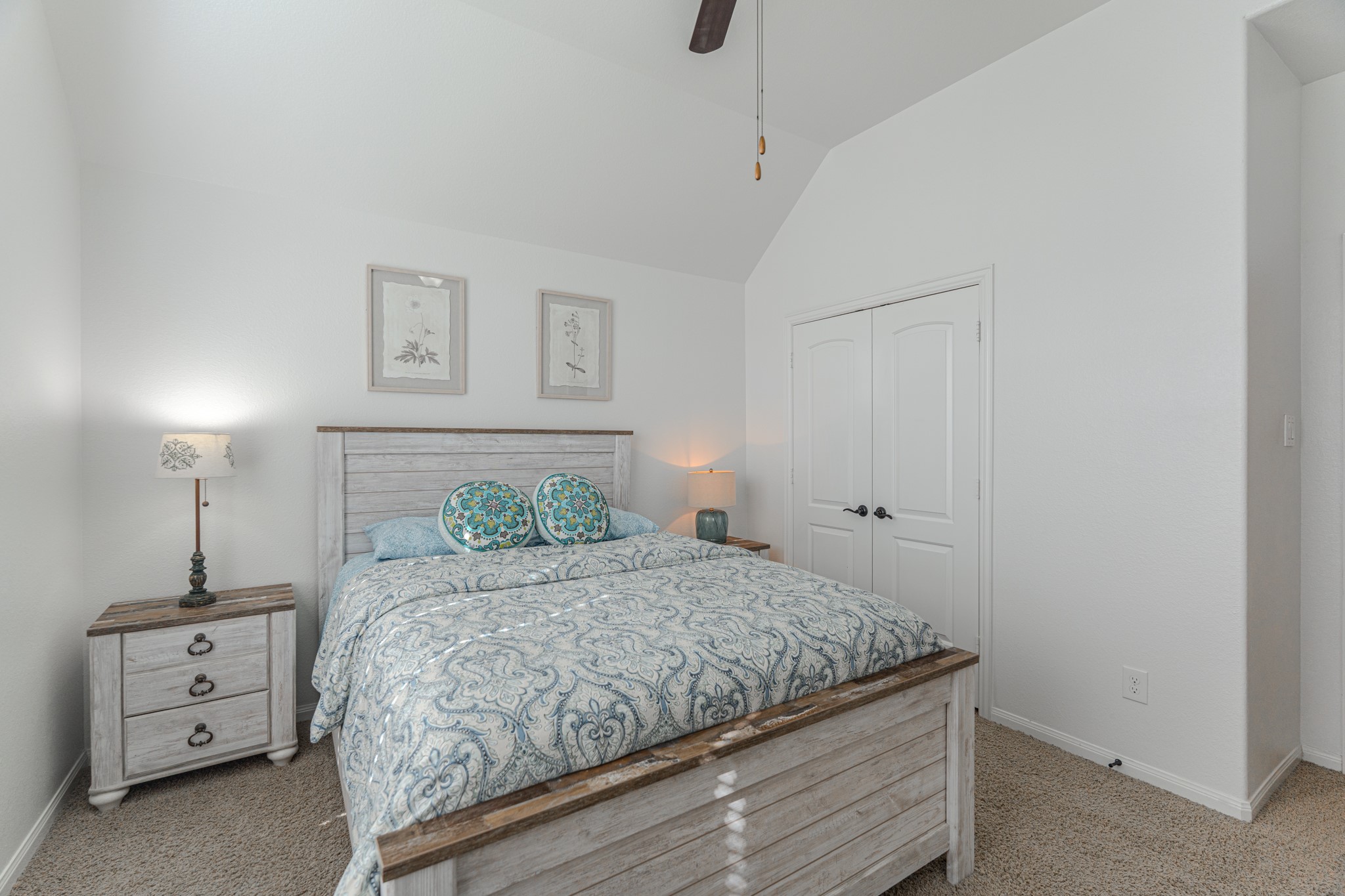 30 Fury Ranch Place The Woodlands, TX 77375 - Photo 35 of 47 This bright, cozy bedroom features a vaulted ceiling, ceiling fan, and large window with blinds. The room is furnished with a comfortable bed, patterned bedding, a nightstand with a lamp, and a decorative chair. Neutral tones and tasteful decor create a welcoming ambiance.