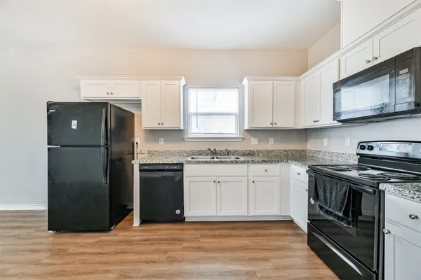 a kitchen with granite countertop a refrigerator stove and sink