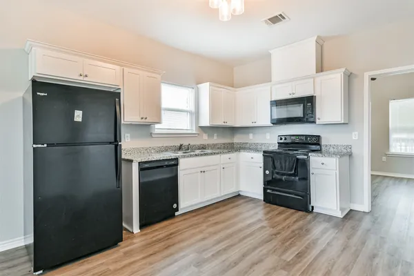 a kitchen with granite countertop a refrigerator stove and microwave