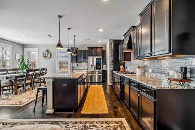 a view of a dining room with furniture a potted plant and windows