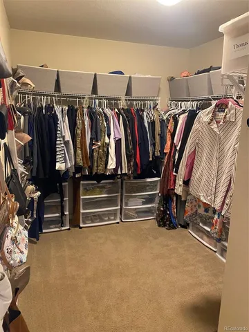 a view of walk in closet with clothes and shoes