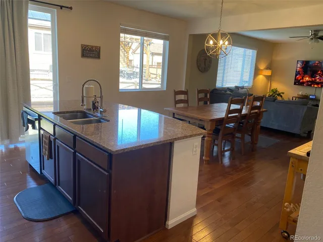 a kitchen with kitchen island granite countertop a sink a stove and a wooden floors