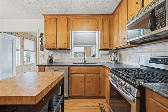 a kitchen with stainless steel appliances a stove a sink a refrigerator cabinets and a dining table