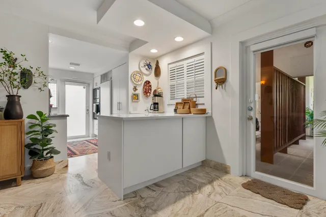 a view of kitchen with stainless steel appliances kitchen island granite countertop cabinets and potted plant